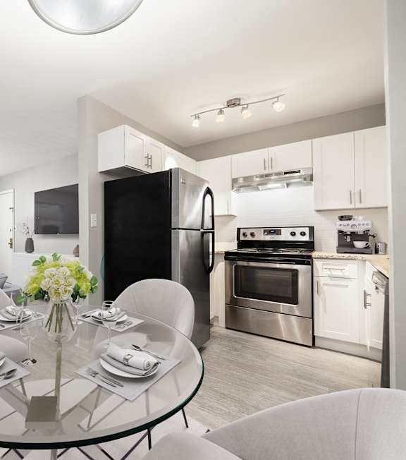 A modern kitchen with a glass dining table set for four  grass at Georgian Oaks Apartments in GA, 30080