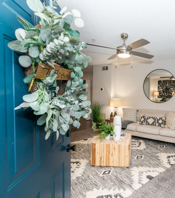 a living room with a blue door and a couch and a ceiling fan