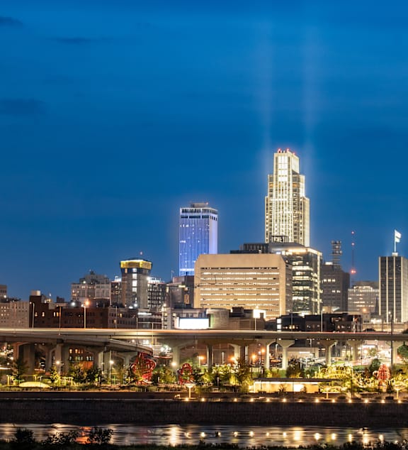 A city skyline at night with a bridge crossing a river.