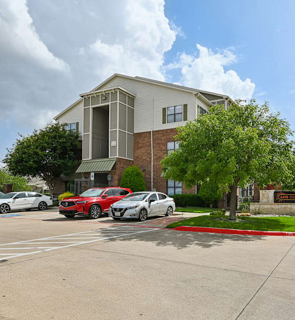 A parking lot with cars and a building in the background.