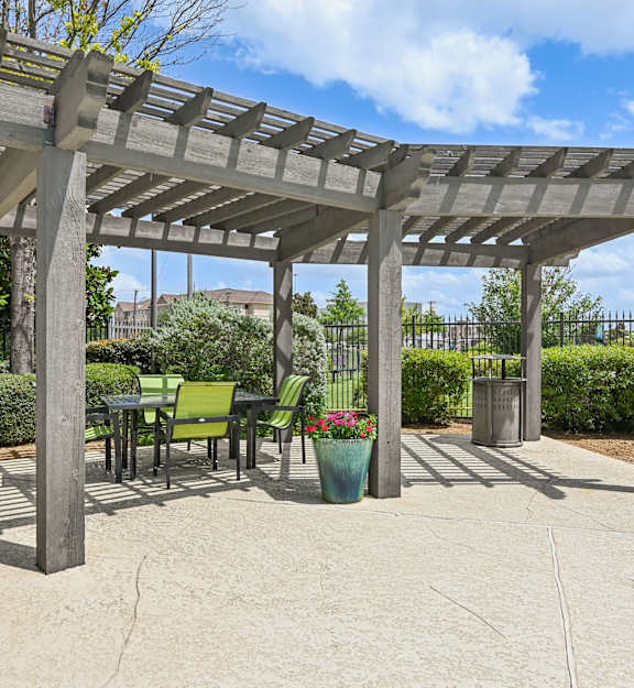 A pergola with chairs and potted plants.