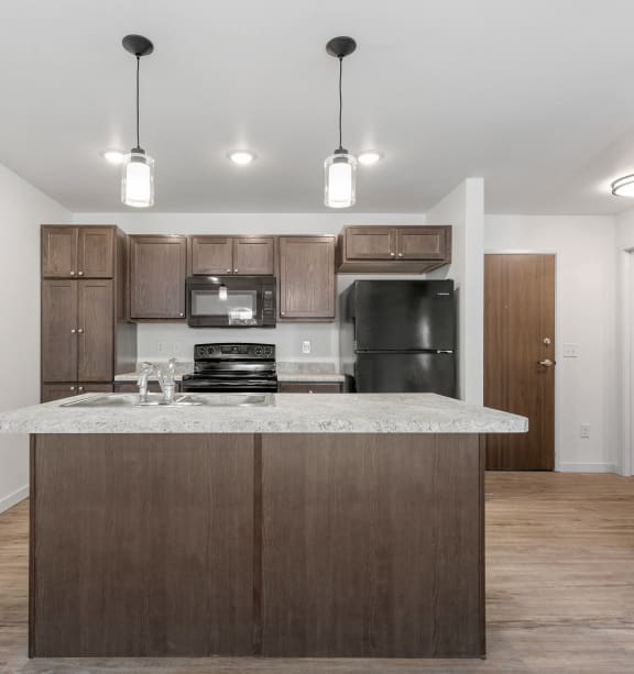 an empty kitchen with a marble counter top and wooden cabinets