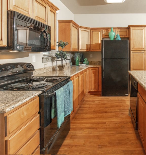 a kitchen with wooden cabinets and granite counter tops and a black refrigerator