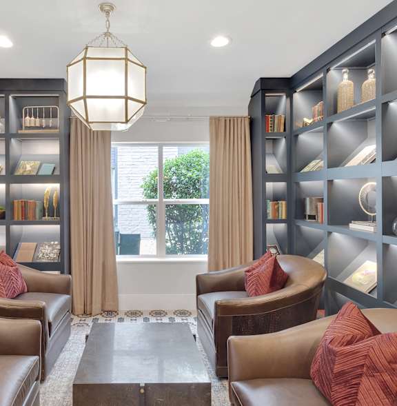 A well-lit room with brown leather chairs and a chandelier.