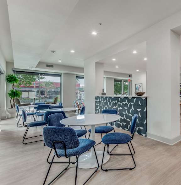 A modern dining room with a white table and blue chairs.