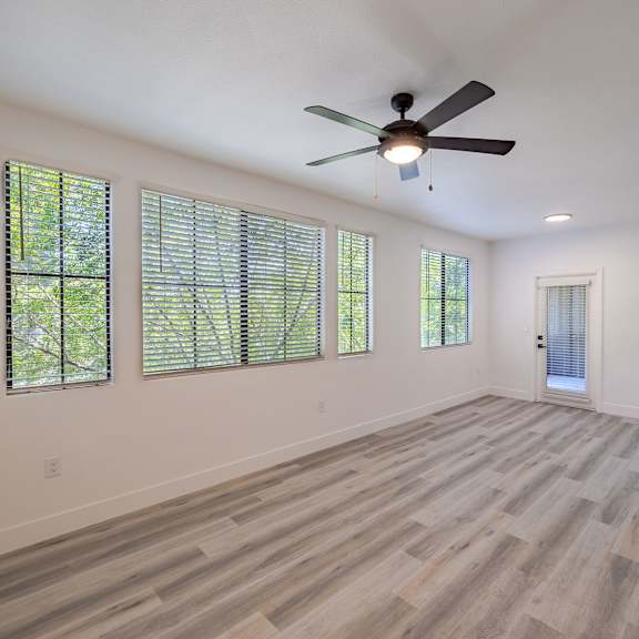 A room with a ceiling fan and wooden flooring.