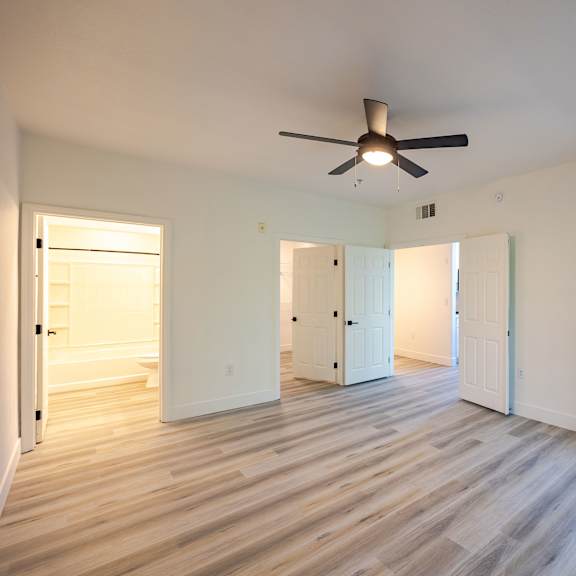 A room with a ceiling fan and wooden flooring.