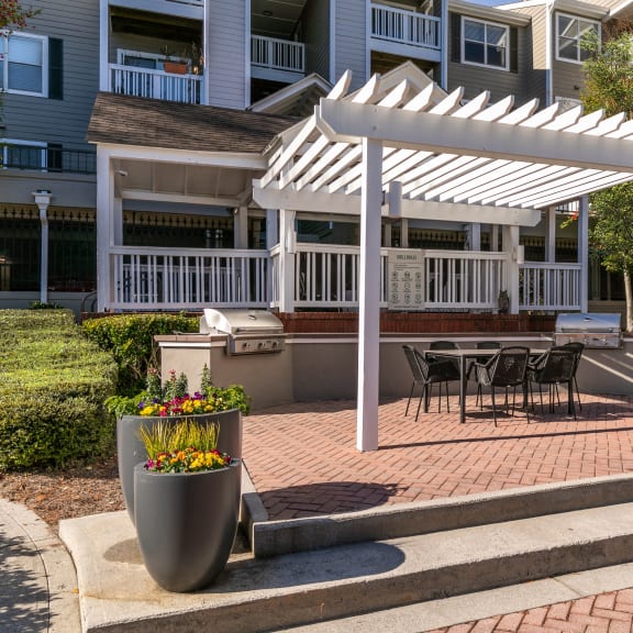 a white pergola on a brick patio with a table and chairs  at Briarcliff Apartments in North Druid Hills, Georgia