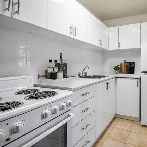 A white kitchen with a stove, sink, and refrigerator.