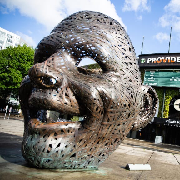 a large metal sculpture in front of a stadium