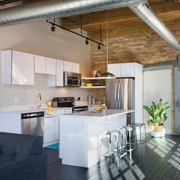 A kitchen with a brick wall and a wooden floor.