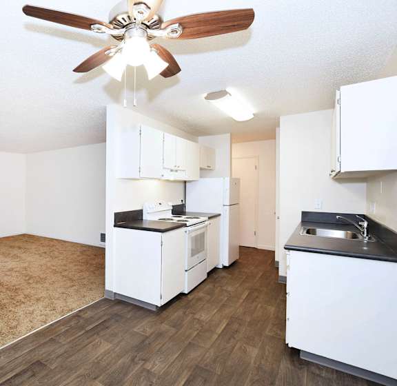 A kitchen with white cabinets and a wood floor.