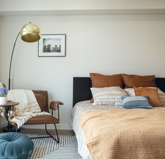 a bedroom with a bed and a chair and a lamp