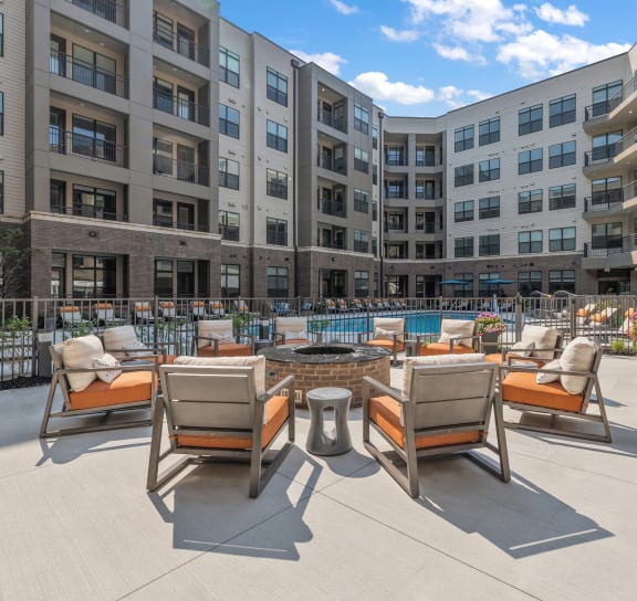 an outdoor lounge area with a fire pit and lounge chairs in front of an apartment building  at The Griffin Royal Oak, Royal Oak, Michigan