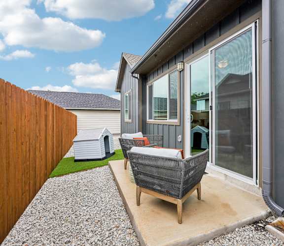 A patio with a wicker chair and a grey couch.