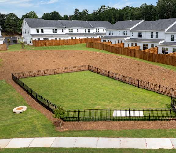 A black fenced in yard with a white house in the background.