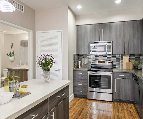 A modern kitchen with stainless steel appliances and wooden floors.