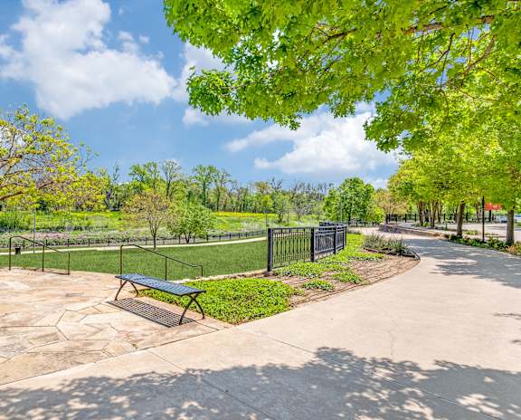 A park with a bench and a fence.