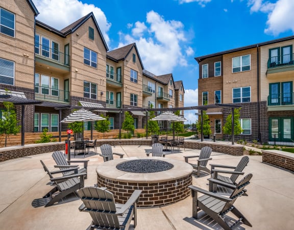 an outdoor patio with chairs and umbrellas in front of apartments
