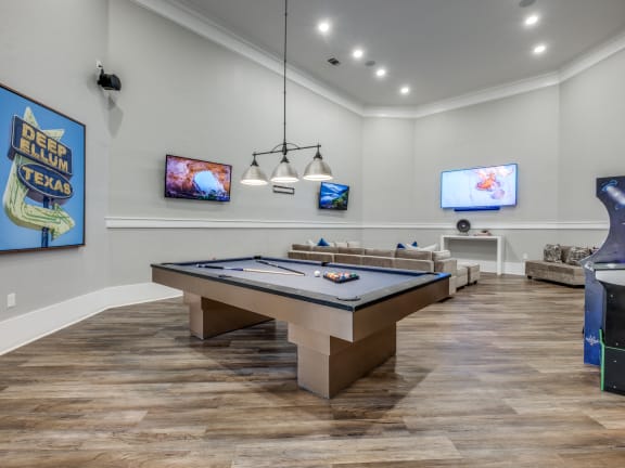 a game room with a pool table and a video game on the wall