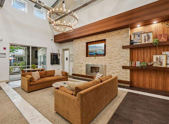 A living room with a stone fireplace and a chandelier.