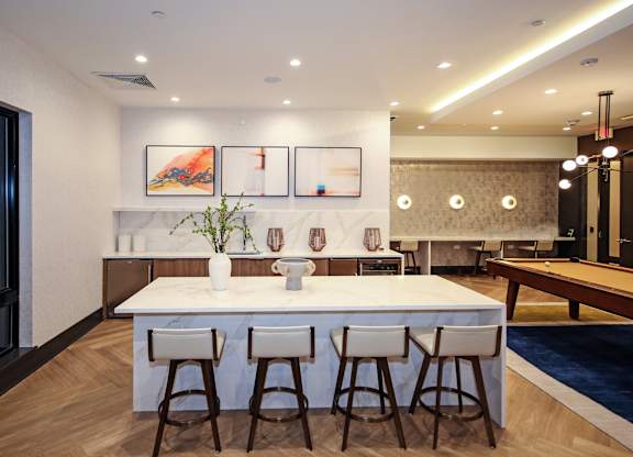 An apartment clubroom catering kitchen with a white island and bar stools.