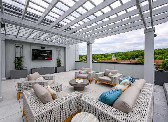 A rooftop patio with white furniture and a white pergola.