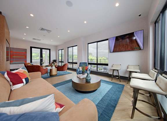 An apartment clubroom with a large couch and a flat screen TV mounted on the wall.