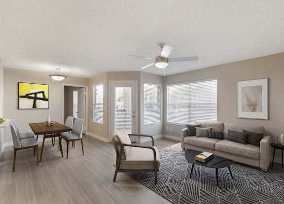 A living room with a grey couch, a coffee table, and a dining table with chairs.