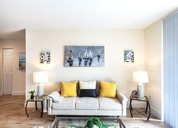 A living room with a grey couch, two lamps, and a painting on the wall.