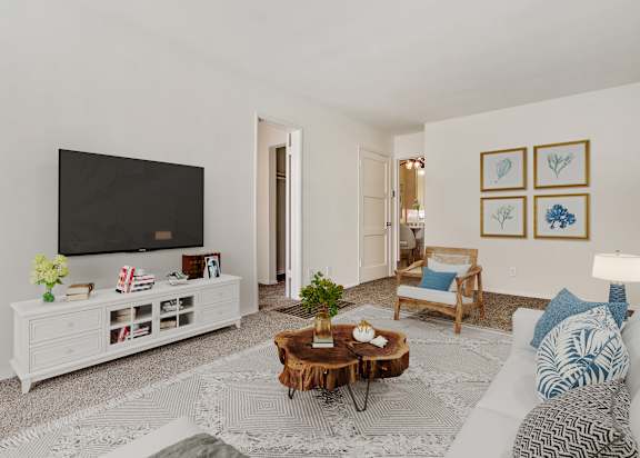 A living room with a white couch, a wooden coffee table, and a flat screen TV.