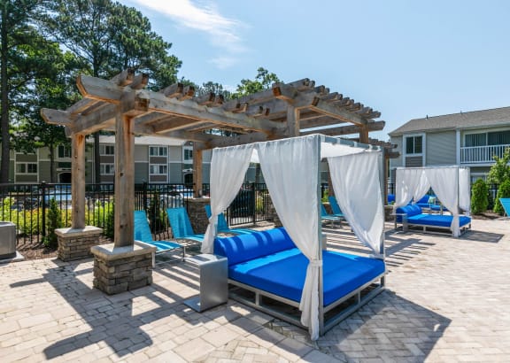 an outdoor lounge area with a pergola and beds