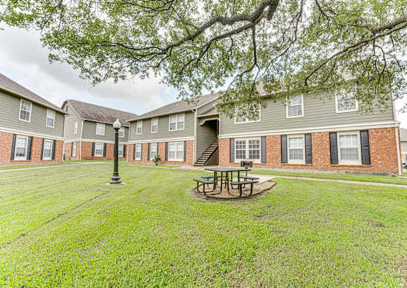 A grassy area with a picnic table in front of a brick building.
