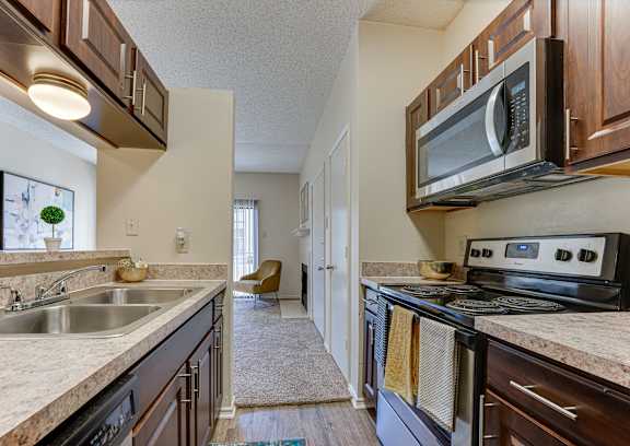 A kitchen with a stove, sink, and microwave.