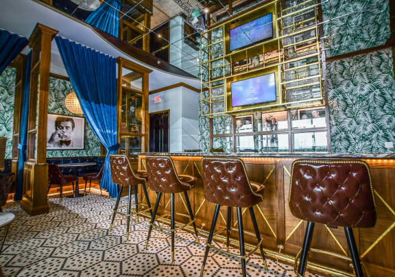a bar with leather chairs and a television on the wall