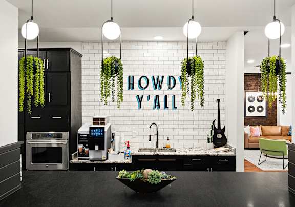 a kitchen with plants on the wall and a howdy yall sign
