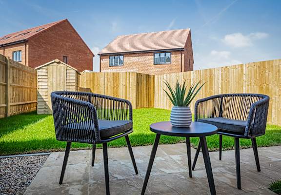 a patio with two chairs and a table in a garden