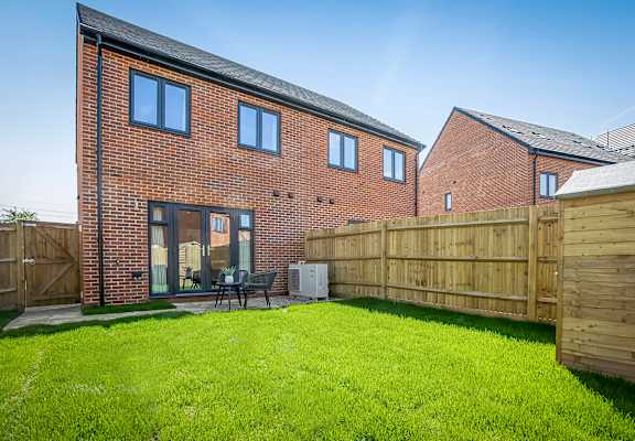 the back of a house with a yard and a wooden fence