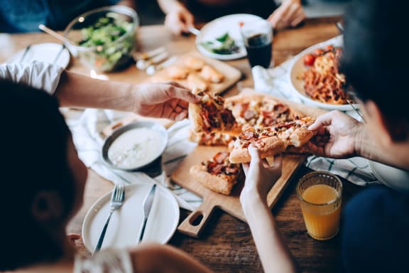 a group of people eating pizza at a table at Pleasanton Place, Pleasanton, CA, 94566