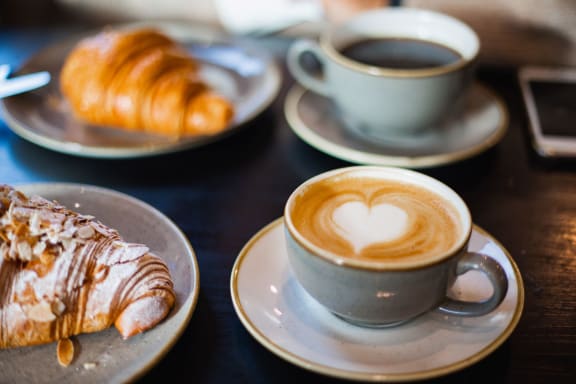 a cup of coffee with a croissant on a table with plates of food at Pleasanton Place, Pleasanton, CA