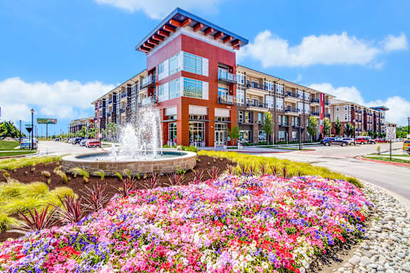 a building with a fountain and flowers in front of it