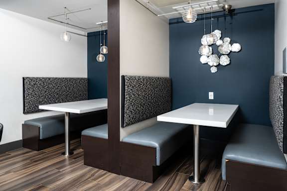 A modern dining area with a white table and grey booths.