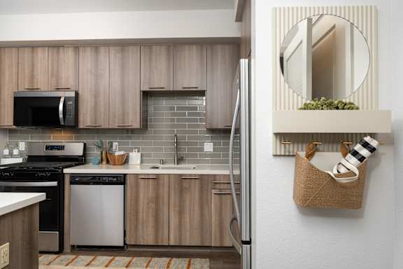 A modern kitchen with wooden cabinets and a black microwave above the stove.