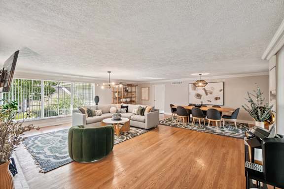 A living room with a green sofa and a wooden floor at Glens of Bloomfield Apartments, Michigan