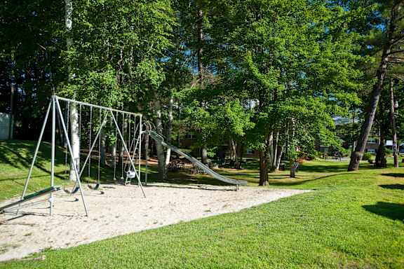 A playground with a slide and swings in a park.