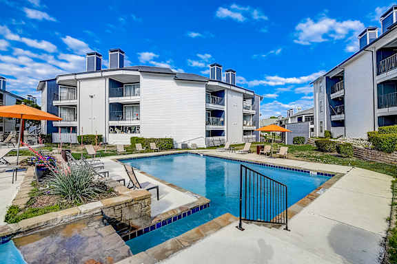 A swimming pool surrounded by a black fence and a white building in the background.