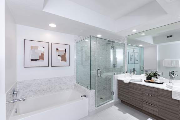 A modern bathroom with a white tub and a glass shower.
