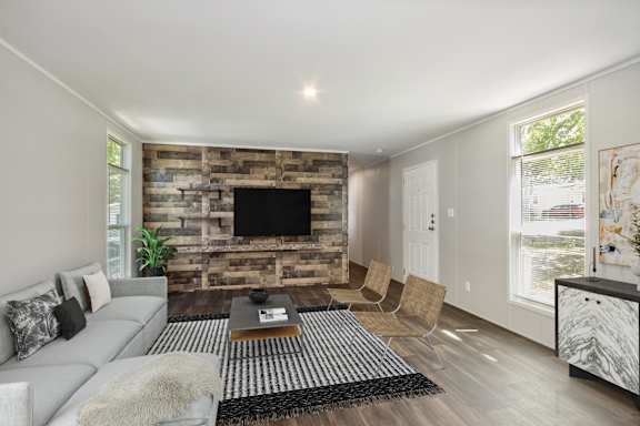 A modern living room with a grey sofa and a wooden wall.