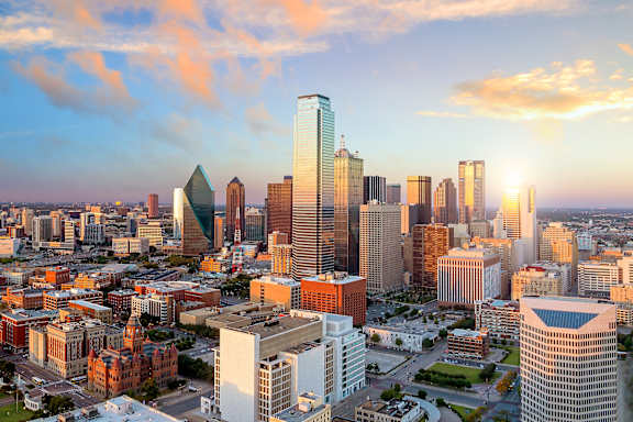 A cityscape with buildings of various shapes and sizes under a sky with clouds at Prairie Crossing, Farmers Branch, TX 75244