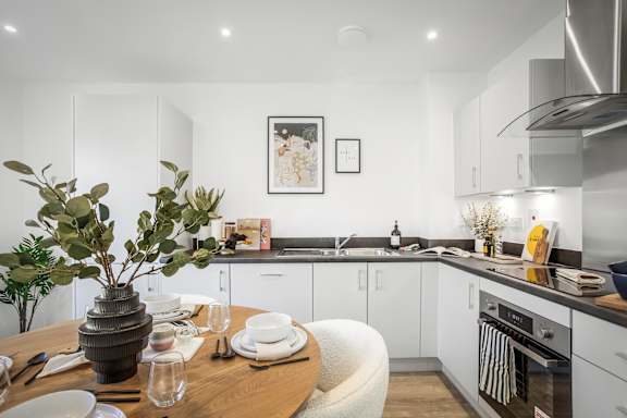 A modern kitchen with a dining table set for two.